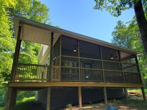 Une cabane en bois dotée d’un balcon, de grandes fenêtres et d’une véranda couverte.
