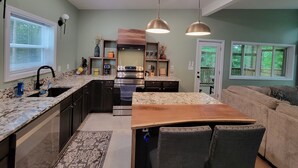 A modern kitchen with granite countertops, a stainless steel range, and a wooden dining table.