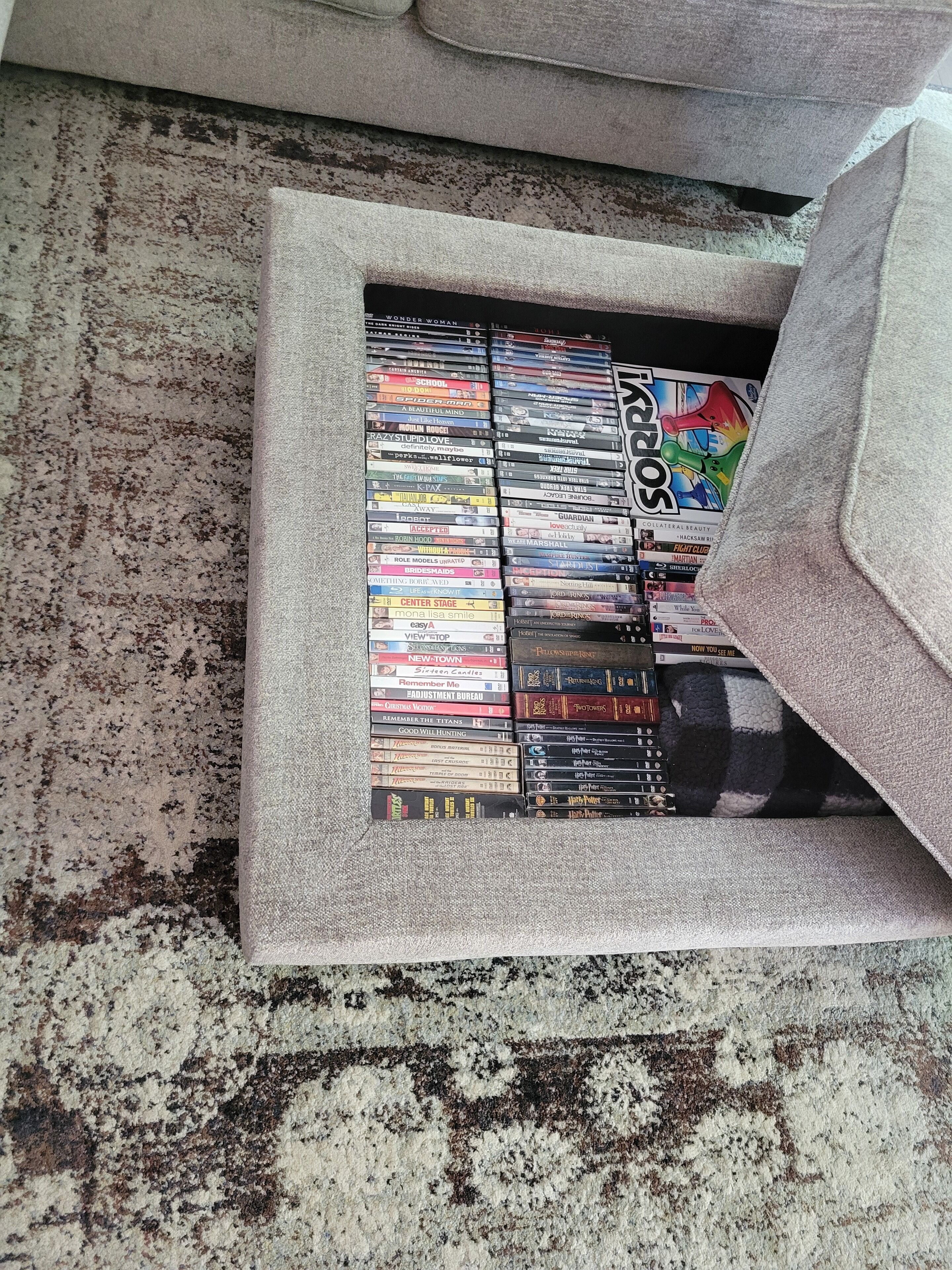 A collection of DVDs in a storage box on a carpeted floor.