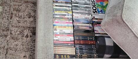 A collection of DVDs in a storage box on a carpeted floor.