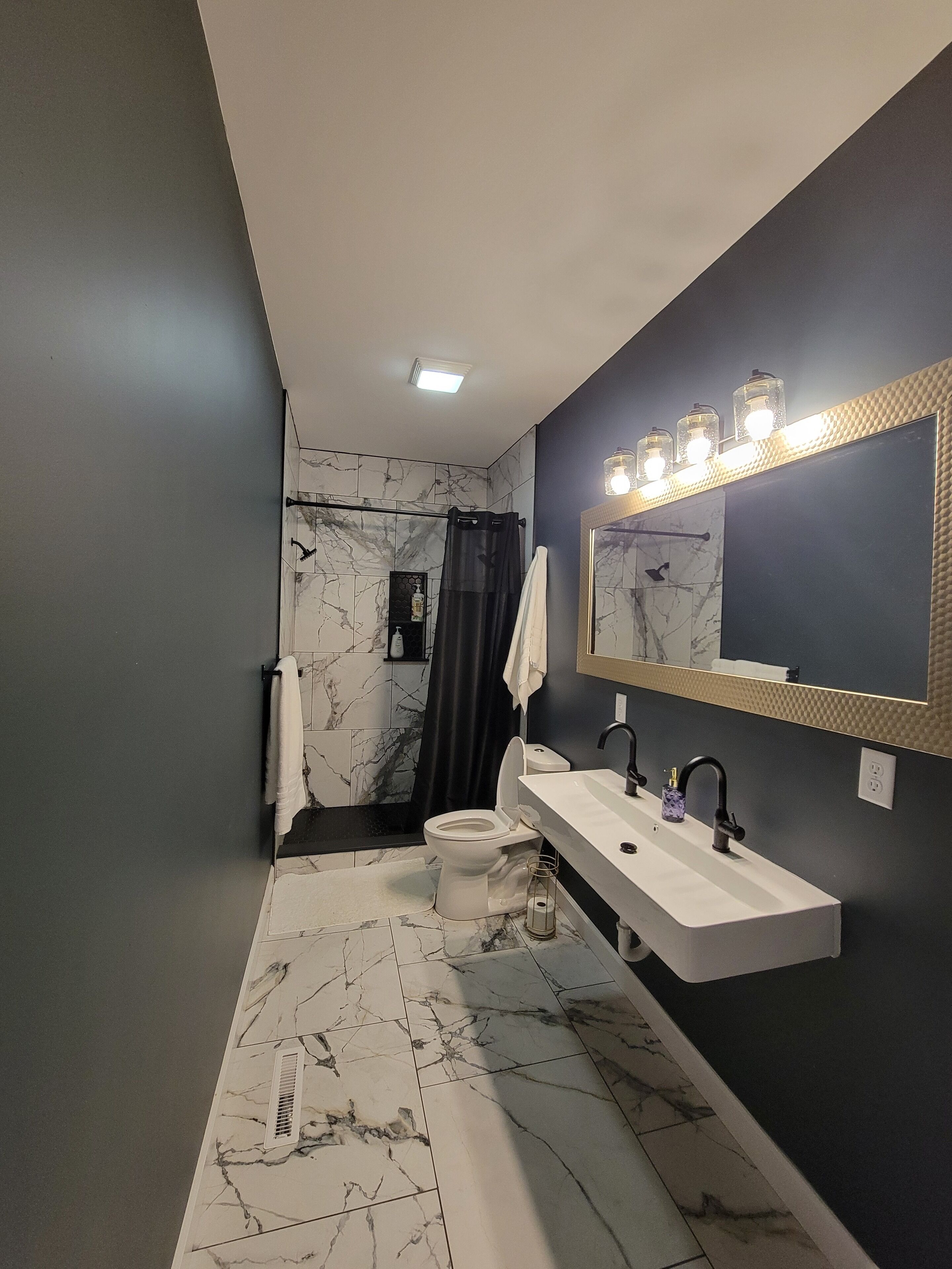 A modern bathroom with a white sink, black faucet, and a marble-patterned floor.