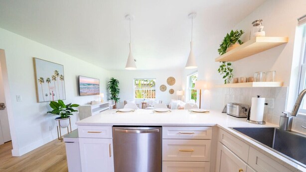 A modern kitchen with a central island, stainless steel appliances, and white cabinetry. - The Canary Palm | Fenced Private Backyard (Bonita Springs)
