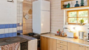 Cocina compacta con estufa, refrigerador y armarios de madera.