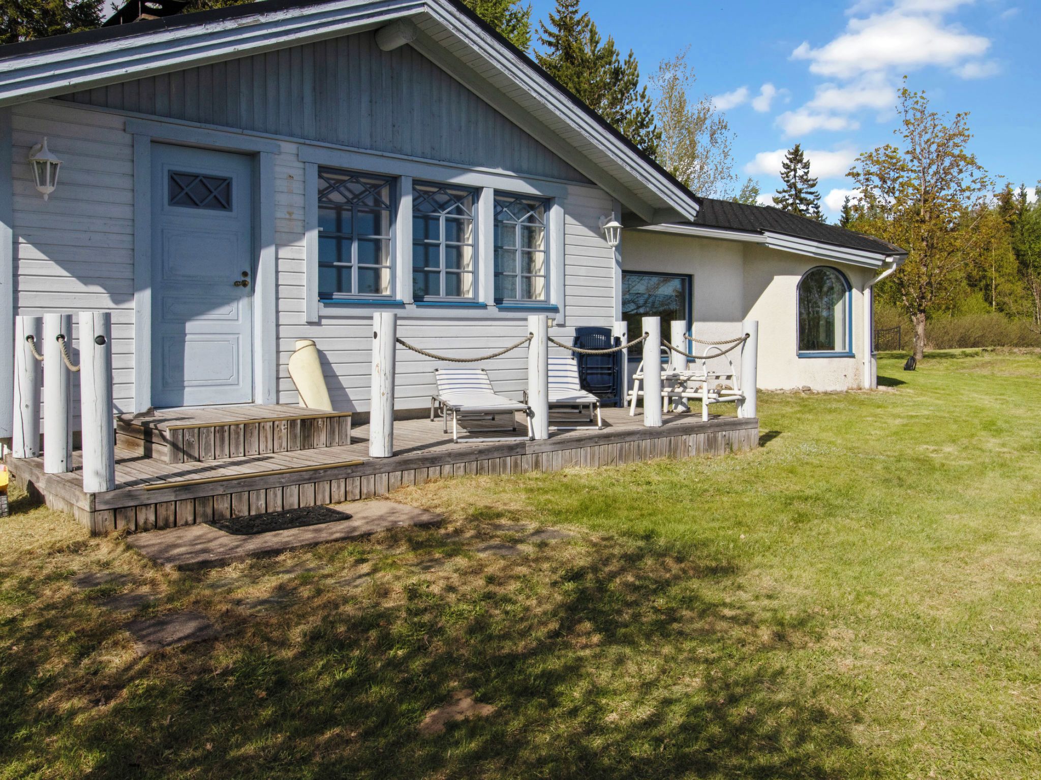 A single-story building with a porch, a small deck, and a covered seating area.