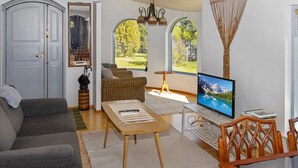 Una sala de estar acogedora con un sofá gris, una mesa de centro de madera y un televisor sobre un mueble.