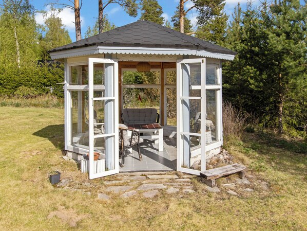 A gazebo with a hexagonal roof, open sides, and a bench inside.