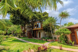 A modern house with a circular glass room, surrounded by lush greenery and a well-maintained lawn. - Rocks Beach Boutique Phu Quoc (Phu Quoc)
