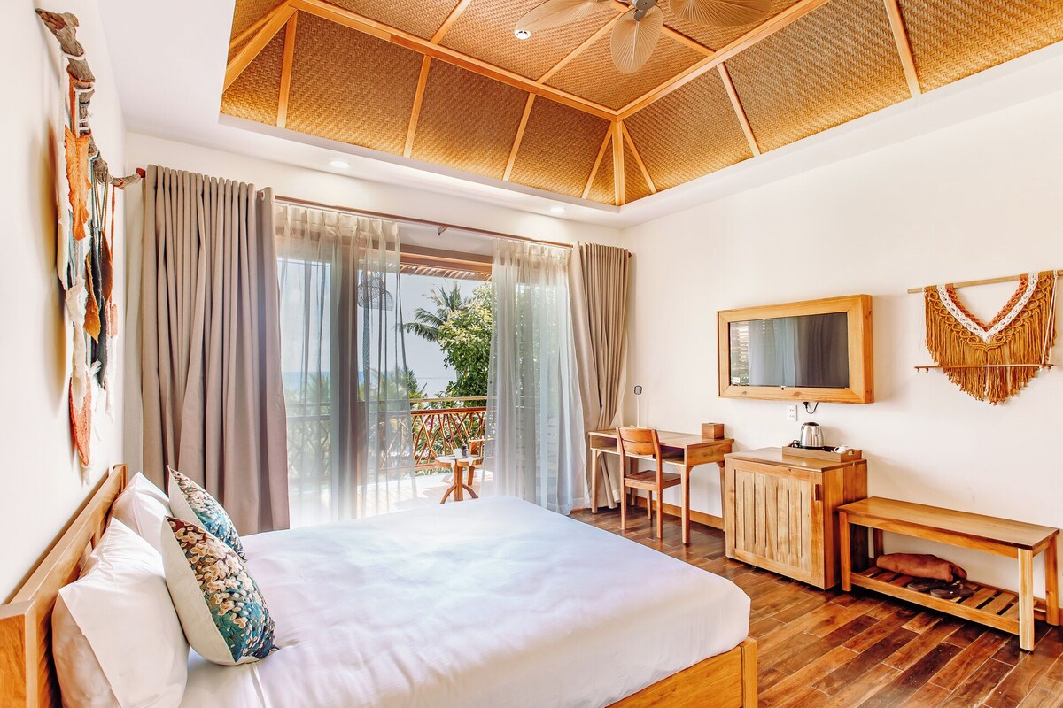 A spacious bedroom with a large bed, a desk, and a TV.