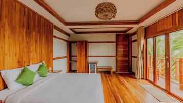 A hotel room with a large bed, wooden walls, a ceiling fan, and a view through the glass doors.
