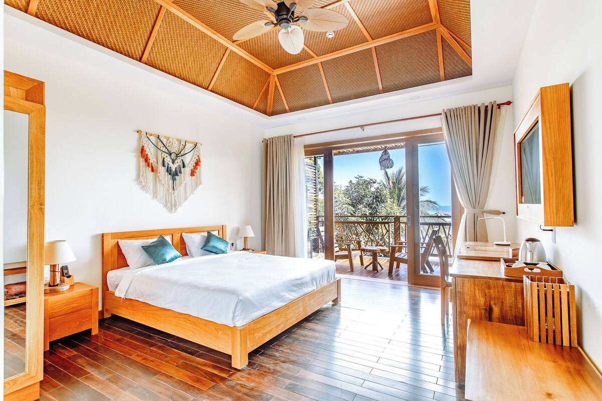A spacious bedroom with a wooden bed, a ceiling fan, and a view of the outdoors.