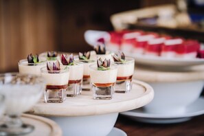 A dessert table with small glass cups containing layered desserts, garnished with edible flowers, and a larger dessert dish in the background. - Rocks Beach Boutique Phu Quoc (Phu Quoc)
