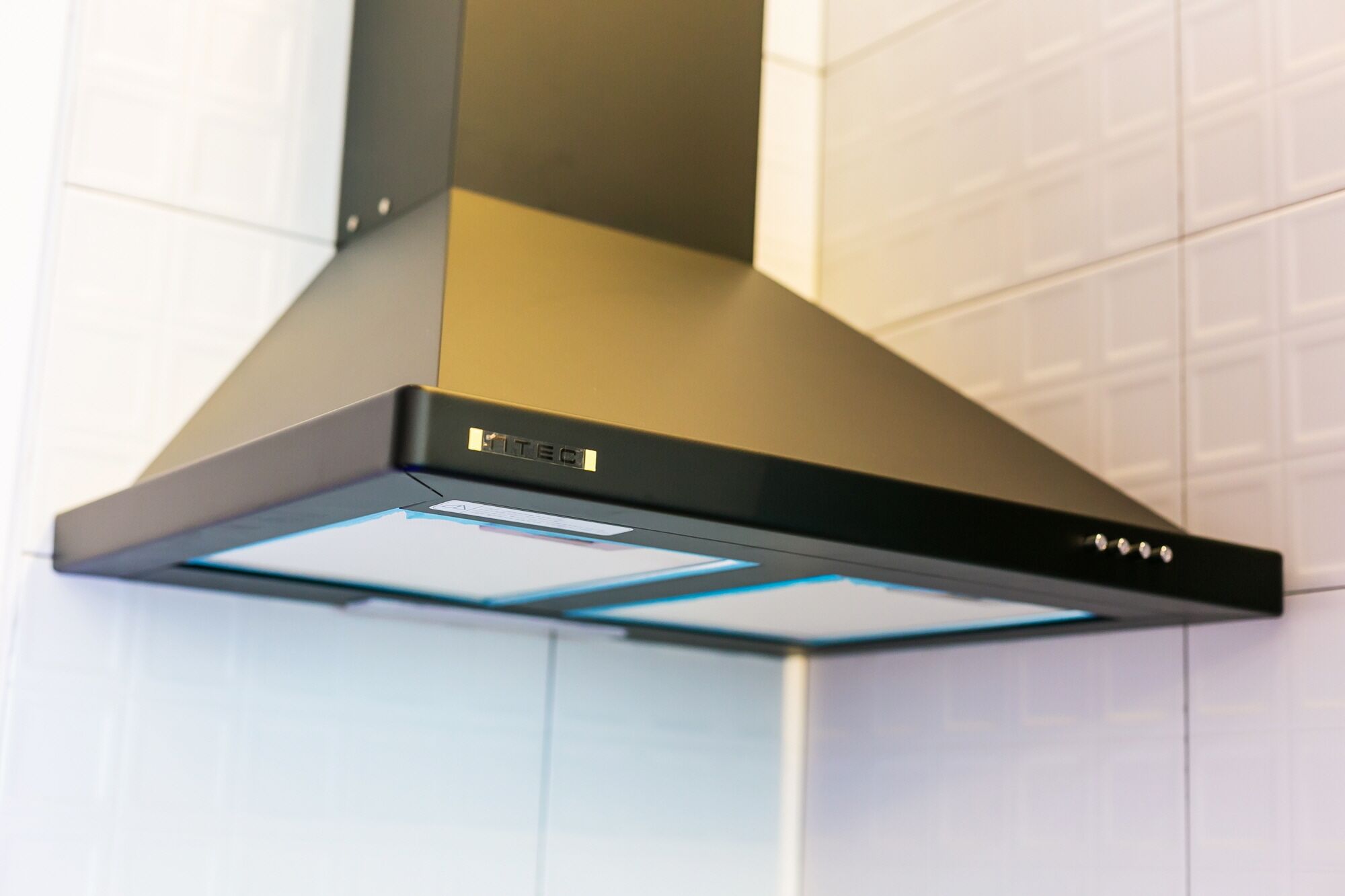 A modern kitchen hood with a sleek design and a visible brand logo.