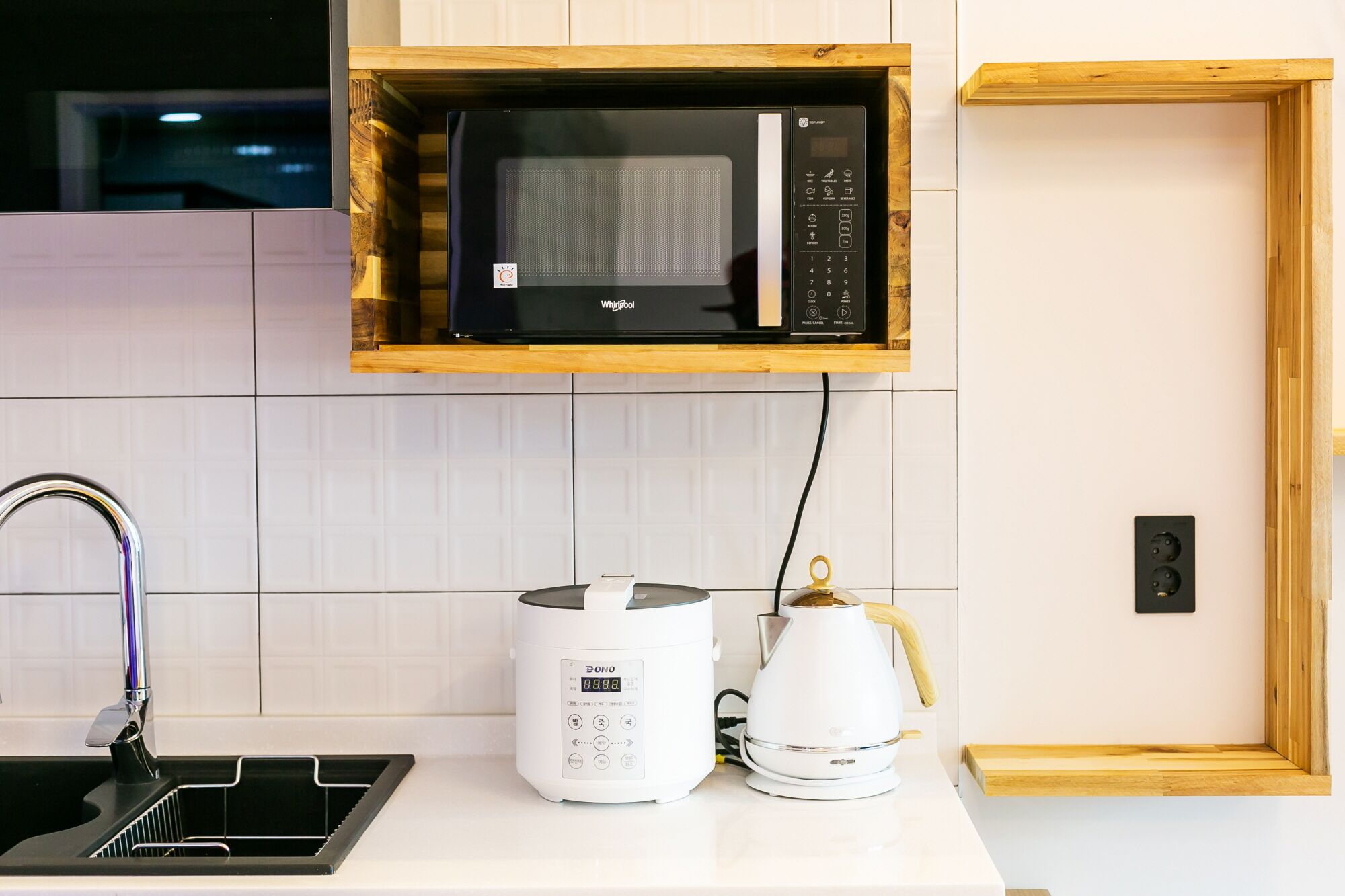 A kitchen with a microwave, a coffee maker, and a kettle on the counter.