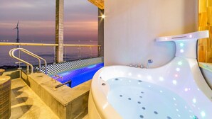 Un área de spa con un jacuzzi y vistas al océano al atardecer.