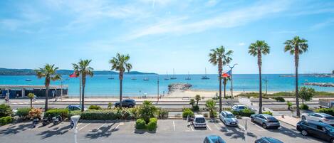 A parking lot with cars and a view of the beach and ocean.