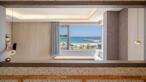 Une chambre moderne dotée d’une grande fenêtre, d’un banc et offrant une vue sur la plage.