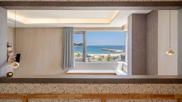 Une chambre moderne dotée d’une grande fenêtre, d’un banc et offrant une vue sur la plage.