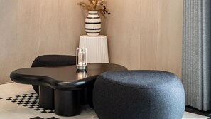 Un espace repas moderne avec une table ronde, des chaises noires et un pouf gris.