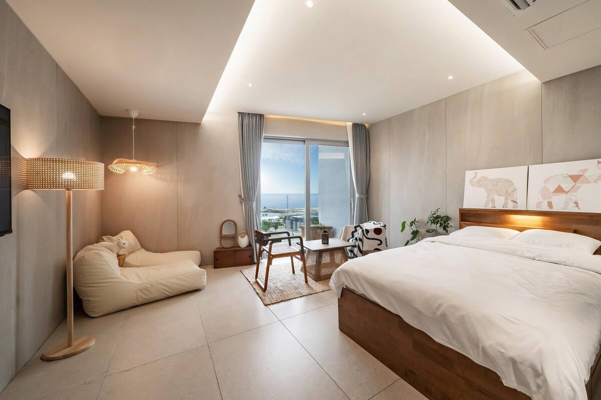 Ein modernes Hotelzimmer mit einem großen Bett, einem Schreibtisch und Meerblick.