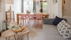A cozy living room with a wooden dining table, pink chairs, a grey sofa, and a coffee table. - La Trouvillaise by Interhome (Deauville-Trouville)