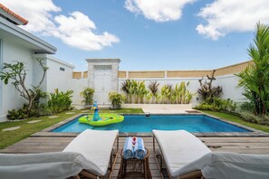 A swimming pool with lounge chairs and a floating toy. - Noel Peaceful 3BR Villa (Munggu)