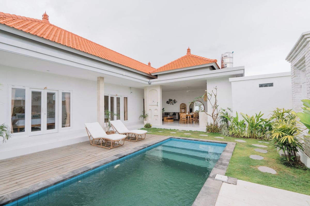 Een modern huis met zwembad, een witte gevel en een terras.