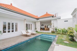 Een modern huis met zwembad, een witte gevel en een terras.