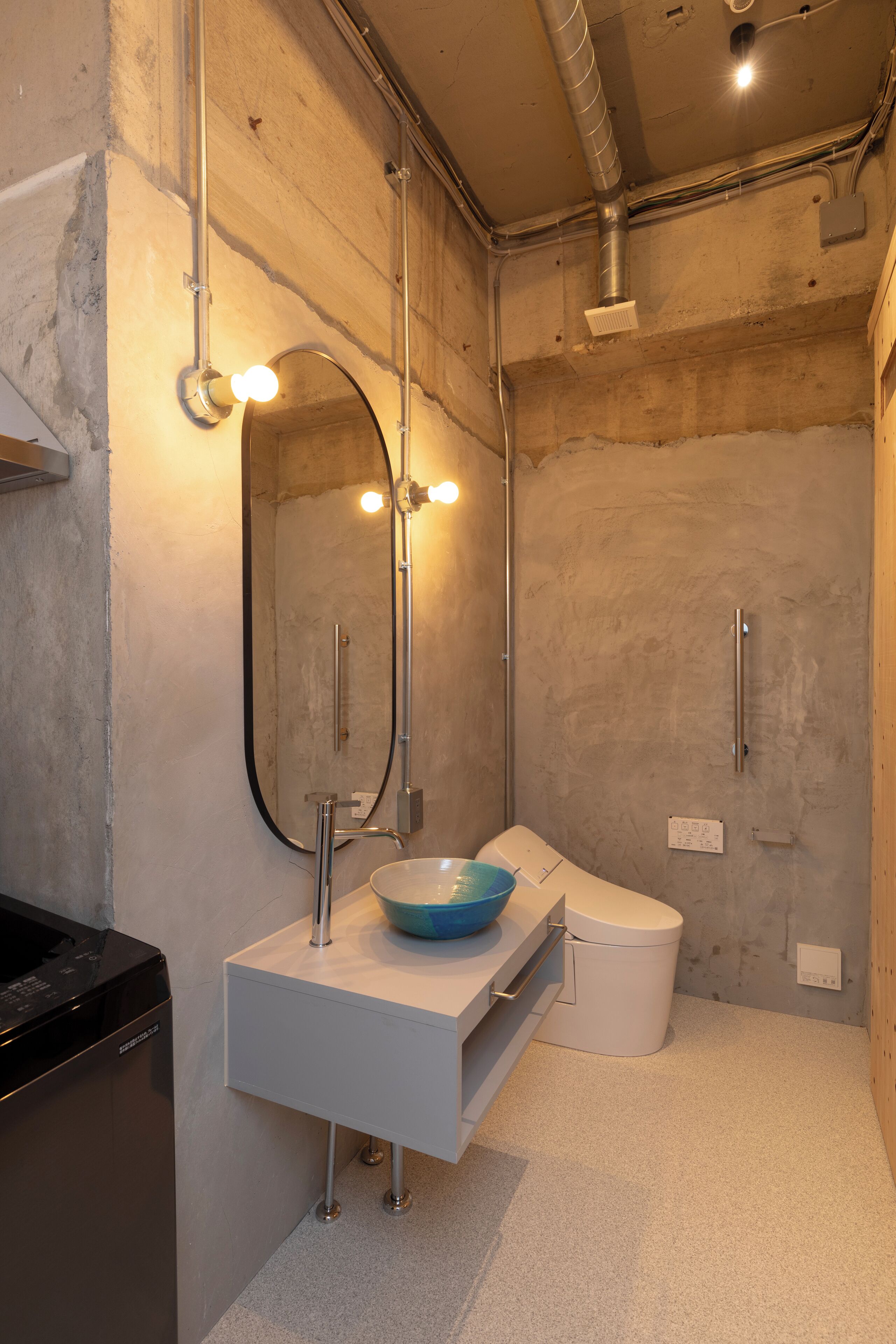 Un baño moderno con un tocador blanco, un lavabo azul, un espejo con luces, un inodoro y una ducha.