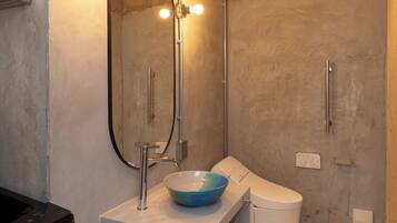 Un baño moderno con un tocador blanco, un lavabo azul, un espejo con luces, un inodoro y una ducha.