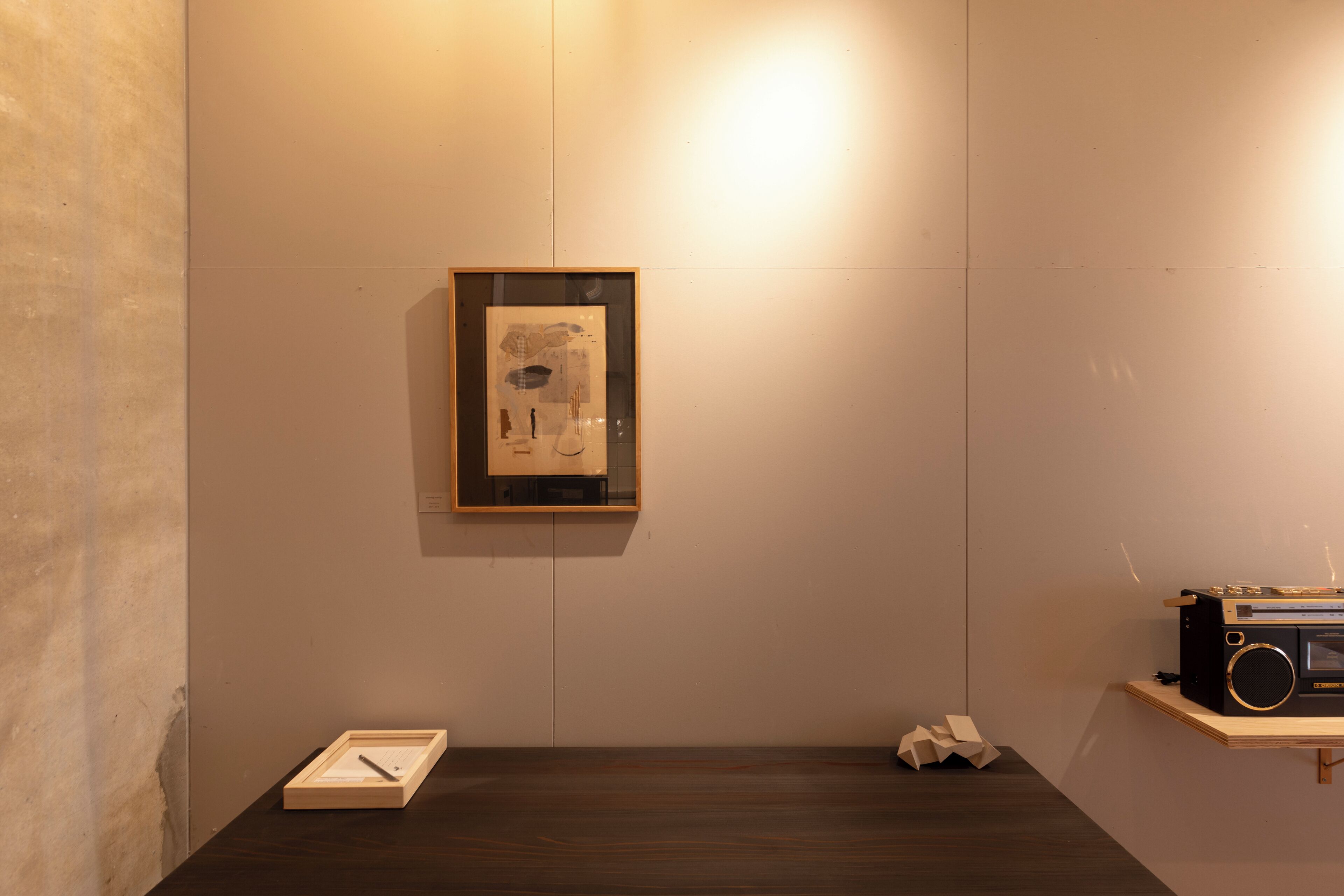 A minimalist room with a wooden floor, a framed artwork on the wall, and a vintage radio on a shelf.