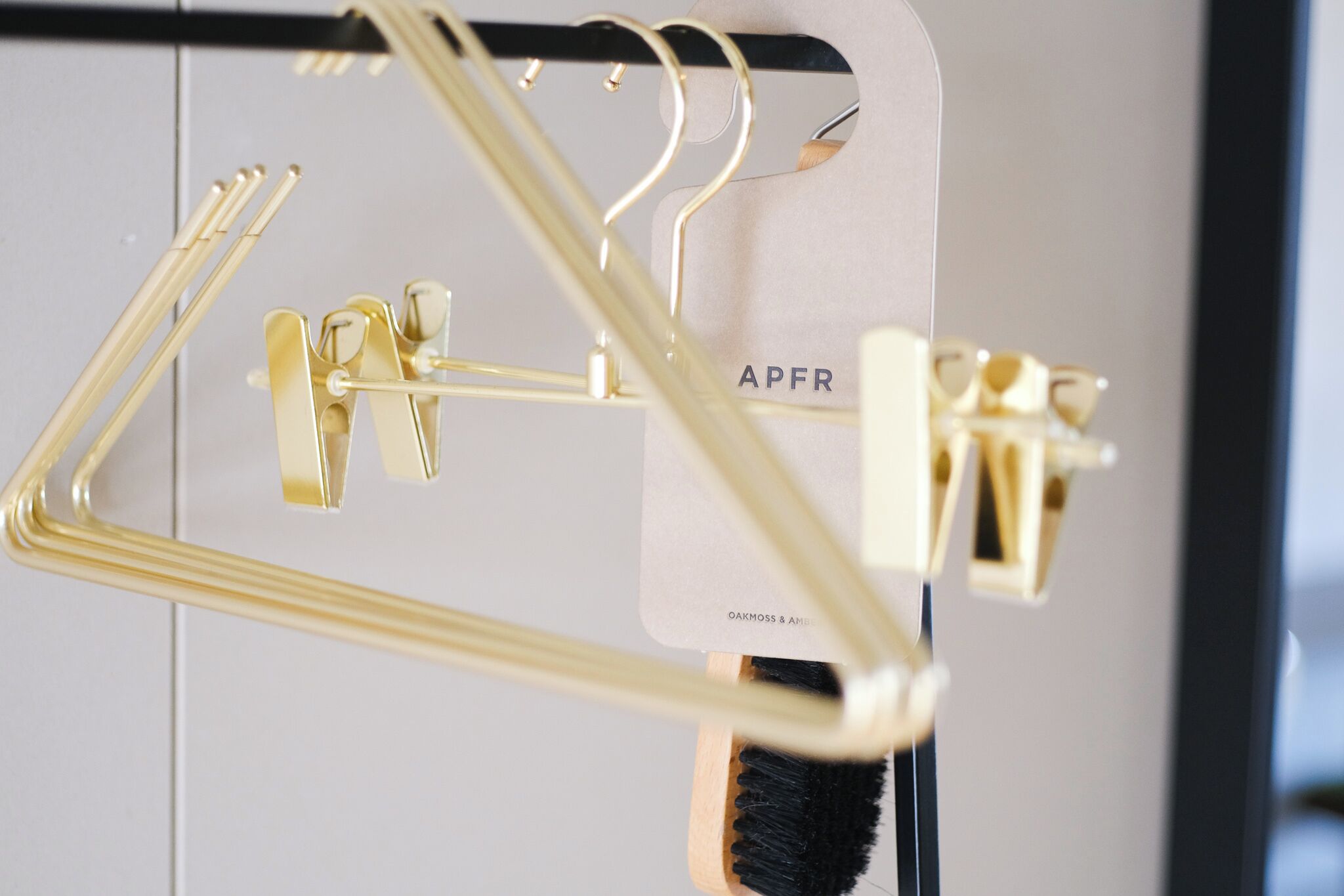 A gold-colored metal rack with hooks and a card labeled "APFR" hanging from it.