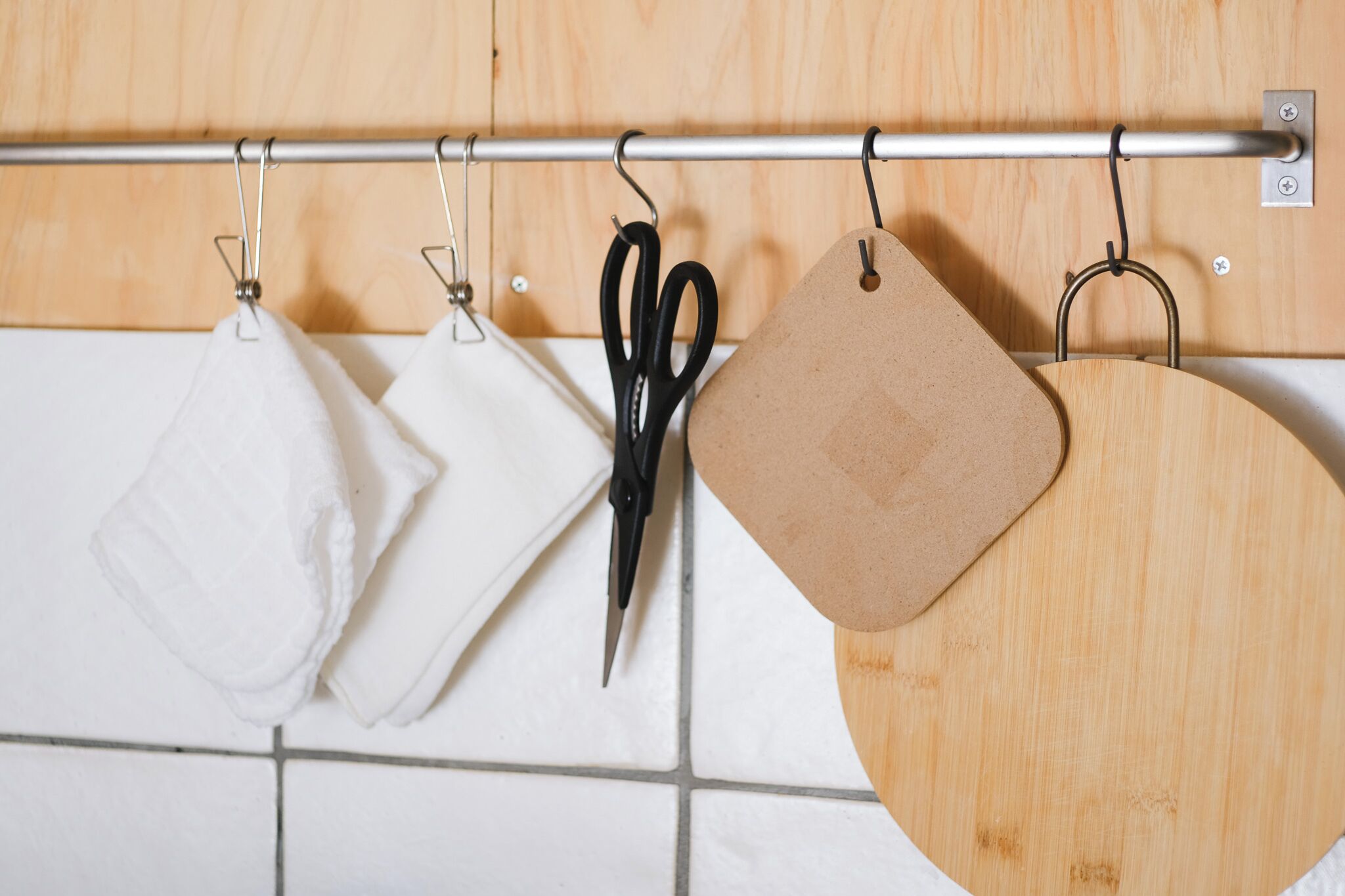 A kitchen with a metal rod holding kitchen towels and a pair of scissors.