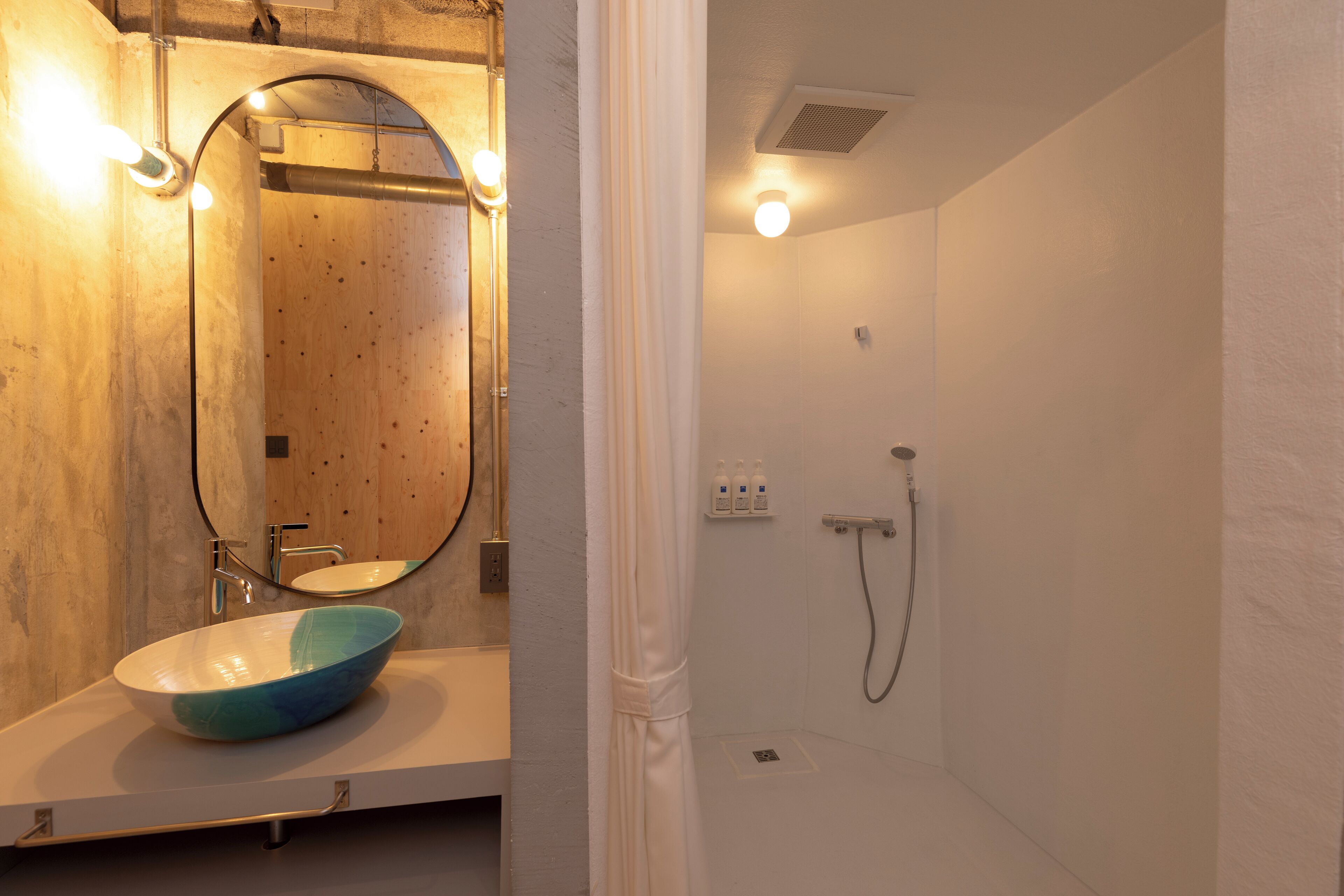 A bathroom with a wooden vanity, a round mirror, and a shower area.