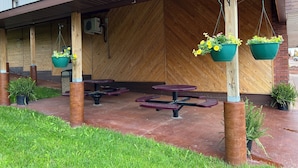 Un espace extérieur aménagé avec des tables de pique-nique et des jardinières suspendues.