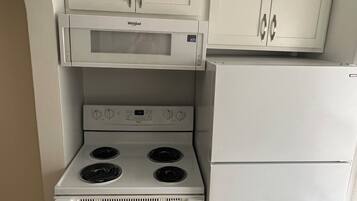 A compact kitchen with a built-in microwave, stove, and refrigerator.