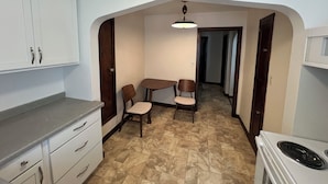 Une cuisine compacte avec un coin repas, comprenant un four encastré, une petite table et deux chaises.