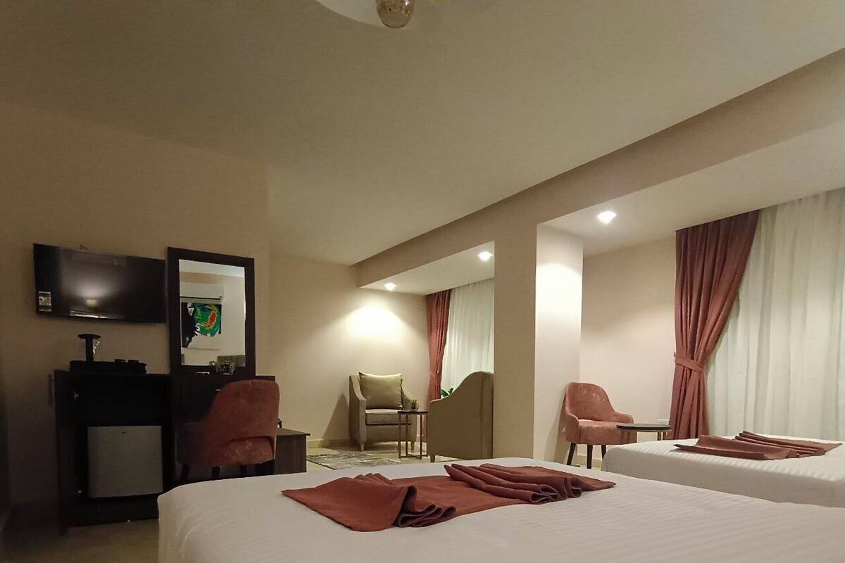 A hotel room with two beds, a television, a desk, and a chair.
