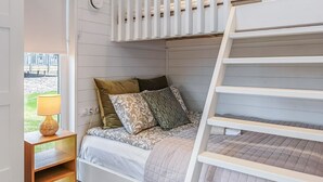 A bunk bed with a ladder, a bedside table with a lamp, and a window with a view of the outdoors. - Villa sirius 56 by Interhome (Kemiönsaari)