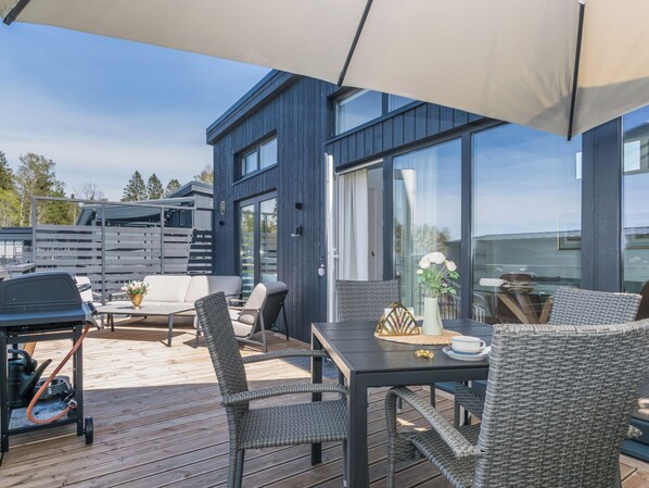 An outdoor deck with a dining area, chairs, and a grill.