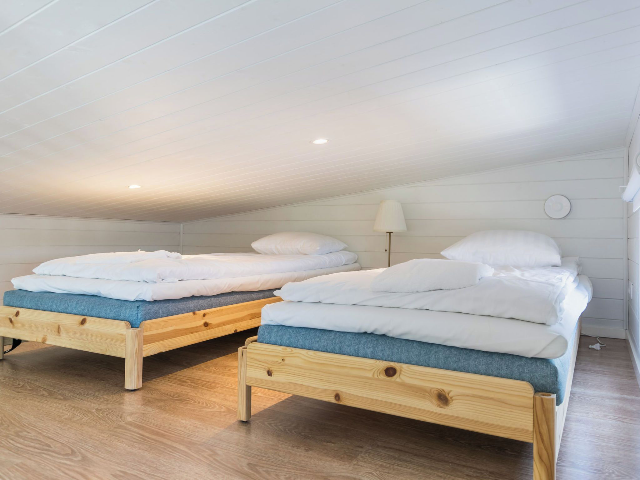 A room with two wooden beds, each with a blue mattress and white bedding.
