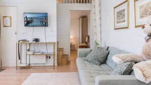 Un salon moderne avec une télévision, un canapé, une table basse et un ours en peluche.