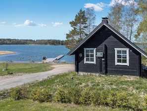Uma cabana com um cais que se projeta sobre um lago, cercada por árvores e um céu limpo.