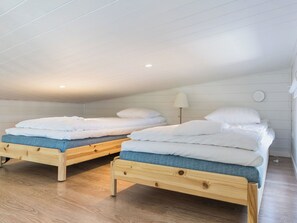A room with two wooden beds, each with a blue mattress and white bedding.
