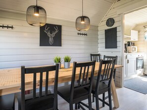 Un comedor con mesa y sillas de madera, luces colgantes y un reloj en la pared.