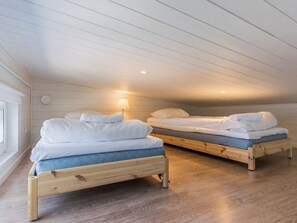 Una habitación con dos literas de madera, cada una con un colchón y almohadas, y una lámpara de noche.