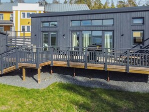 Ein modernes Gebäude mit Terrasse, Sitzgelegenheiten im Freien und Blick auf das Wasser.