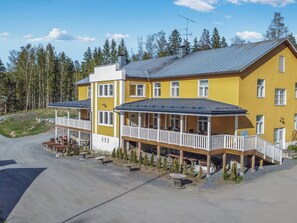 A two-story yellow building with a balcony and outdoor seating area.
