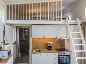 A compact kitchen with a built-in oven, a coffee maker, and a sink.