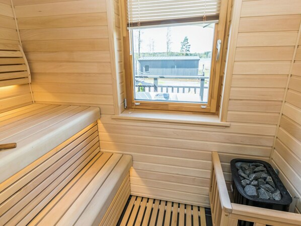 A sauna room with a bench, a window, and a stone tray.