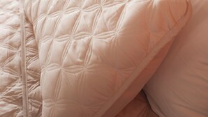 Een bed met een gewatteerd hoofdbord en meerdere kussens.